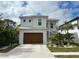 Two-story house with white exterior, brown garage door, and landscaping at 1840 Douglas Ave, Dunedin, FL 34698