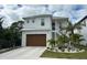 Two-story house with white exterior, brown garage door, and landscaping at 1840 Douglas Ave, Dunedin, FL 34698