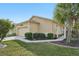 Tan house exterior with a two-car garage and lush landscaping at 21042 Diamonte Dr, Land O Lakes, FL 34637