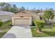 Tan one-story house with a red tile roof, two-car garage, and well-manicured lawn at 21042 Diamonte Dr, Land O Lakes, FL 34637