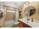 Well-lit bathroom featuring a vanity sink, a round mirror and a tiled tub with shower at 2902 Big Cypress Way, Wesley Chapel, FL 33544