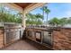 Outdoor kitchen featuring built-in grill, refrigerator, sink, and stone backsplash at 2902 Big Cypress Way, Wesley Chapel, FL 33544