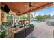 Covered patio with wood ceiling, comfortable seating, outdoor kitchen, and view of the pool at 2902 Big Cypress Way, Wesley Chapel, FL 33544