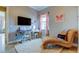 Well-lit bedroom with plush chaise lounge, window with pink curtains, and writing desk at 6367 Foxbrook Trl, Parrish, FL 34219