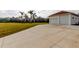 Spacious garage and driveway featuring lush landscaping and mature palm trees, providing a sense of privacy and serenity at 6367 Foxbrook Trl, Parrish, FL 34219