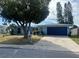 Ranch-style home with blue exterior, attached garage, and mature landscaping at 7524 Vienna Ln, Port Richey, FL 34668