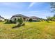 Backyard with a well-maintained lawn, mature landscaping and neutral toned exterior that blends into nature at 11125 Callisia Dr, Odessa, FL 33556