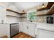 Modern white kitchen with wood shelving, quartz countertops, and stainless steel appliances at 1511 Prescott S St, St Petersburg, FL 33712