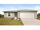 Gray house with white garage door, landscaping, and driveway at 19474 Strathcona Ave, Port Charlotte, FL 33954