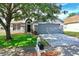 Charming single-story home with a manicured lawn, mature tree, and a two-car garage at 4317 Knollcrest Ct, Spring Hill, FL 34609