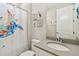 Clean bathroom with a single sink vanity, neutral tile, and a sea turtle-themed shower curtain at 4909 4Th N Ave, St Petersburg, FL 33710