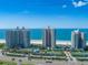 An aerial view showcasing beachfront condos with a pool, tennis courts, and ocean views at 1520 Gulf Blvd # 1602, Clearwater Beach, FL 33767