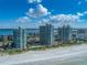 An aerial view showcasing beachfront condos with a pool, tennis courts, and ocean views at 1520 Gulf Blvd # 1602, Clearwater Beach, FL 33767