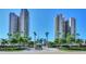 Grand condominium entrance with palm trees, manicured landscaping, and clear blue skies at 1520 Gulf Blvd # 1602, Clearwater Beach, FL 33767