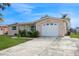 Front view of a single story house with a white garage door and landscaped lawn at 3034 Domino Dr, Holiday, FL 34691