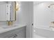 Modern bathroom showcasing a gray vanity with gold fixtures and a white-tiled shower/tub combo at 120 25Th N Ave, St Petersburg, FL 33704