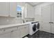 Modern laundry room featuring white cabinetry, a sink, and a large window for ample natural light at 120 25Th N Ave, St Petersburg, FL 33704