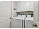 Clean laundry room with white cabinets and modern washer and dryer at 1455 Briarwood Ct, Safety Harbor, FL 34695