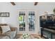 Bright living room with French doors leading to a patio, and a large TV at 1455 Briarwood Ct, Safety Harbor, FL 34695