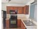 Kitchen with dark wood cabinets, black appliances, and double sink at 2566 Sea Wind Way, Clearwater, FL 33763