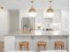Kitchen island with marble countertop, brass pendant lights and white cabinets at 280 N Julia Cir, St Pete Beach, FL 33706