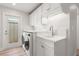 Laundry room with white cabinetry, washer and dryer, utility sink and backyard access at 280 N Julia Cir, St Pete Beach, FL 33706