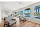 Bright living room featuring wood floors, modern furnishings, and expansive windows overlooking the pool and waterfront at 280 N Julia Cir, St Pete Beach, FL 33706