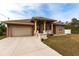 House exterior featuring a tan stucco facade, attractive landscaping, and a two-car garage at 3391 Knox Ter, Port Charlotte, FL 33948