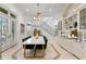Bright dining area with marble table, modern chandelier, staircase with decorative wrought iron, and storage cabinets at 4407 W Dale Ave, Tampa, FL 33609