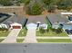 Three-house aerial view showing homes with gray roofs, two-car garages, and well-manicured lawns at 711 Old Windsor Way, Spring Hill, FL 34609
