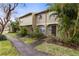 Two story tan townhome with lush landscaping at 7606 Woodbridge Blvd, Tampa, FL 33615