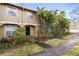 Tan townhome with a landscaped yard and walkway at 7606 Woodbridge Blvd, Tampa, FL 33615