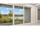 Sliding glass doors offer a picturesque view of a tranquil lake and lush green landscape at 11498 Boundless Ter, Venice, FL 34293