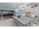 Bright kitchen with white cabinets, modern lighting, and a large island overlooking an outdoor dining area at 1902 4Th E St, Palmetto, FL 34221