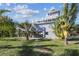 Charming stilt home featuring a large deck, lush greenery, and tropical landscaping at 3476 Tidewater Dr, Weeki Wachee, FL 34607