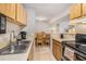 Cozy kitchen featuring wood cabinets, tile floors, and essential appliances with an adjacent dining area at 455 Alt 19 S # 268, Palm Harbor, FL 34683