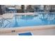 Community pool featuring crystal-clear water, lounge chairs, tables, and a nearby fence and buildings at 16211 Rambling Vine W Dr, Tampa, FL 33624