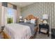 Guest bedroom with a wicker bed frame and patterned wallpaper at 29571 Velletri Ln, Wesley Chapel, FL 33545