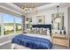 Spacious main bedroom with large windows, a navy bed, and a chandelier at 29571 Velletri Ln, Wesley Chapel, FL 33545