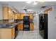 Modern kitchen with wood cabinets, black appliances, and tile floors at 4925 Beacon Hill Dr, New Port Richey, FL 34652