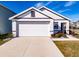 White house with brown accents, a two-car garage, and well-manicured landscaping at 682 Olive Conch St, Ruskin, FL 33570