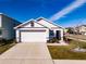 White house with brown accents, a two-car garage, and well-manicured landscaping at 682 Olive Conch St, Ruskin, FL 33570