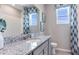 Modern bathroom with granite countertop, gray cabinets, and blue patterned curtains at 691 157Th E Ct, Bradenton, FL 34212