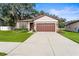 House exterior featuring a brown garage door, landscaping, and a paved driveway at 15571 Stone House Dr, Brooksville, FL 34604