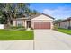 House exterior with brown garage door, landscaping, and a paved driveway at 15571 Stone House Dr, Brooksville, FL 34604