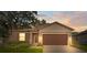 House exterior at dusk showcasing a brown garage door and well-maintained lawn at 15571 Stone House Dr, Brooksville, FL 34604