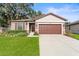 Exterior of a one-story house with a brown garage door and green lawn at 15571 Stone House Dr, Brooksville, FL 34604