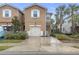 Tan two-story townhome with white garage door and landscaping at 17841 Althea Blue Pl, Lutz, FL 33558