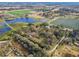 Picturesque aerial view of houses near a serene pond, bordered by vibrant farmland and lush greenery at 1802 Mcgee Rd, Plant City, FL 33565