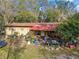 Single-story home featuring mature trees, a metal roof, and a cozy front porch surrounded by lush landscaping at 1802 Mcgee Rd, Plant City, FL 33565